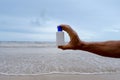 white mockup sunscreen cream, lotion bottle in tanned male hand, sea waves in background, summer sun protection template scene