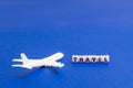 White model of passenger plane on blue background with cube word TRAVEL, diagonally, copy space. Royalty Free Stock Photo
