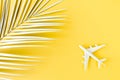 White model plane, airplane and palm leaf on yellow background. Top view, flat lay. Travel, vacation concept. Royalty Free Stock Photo