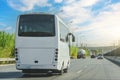 White modern comfortable tourist bus driving through highway at bright sunny day. Travel and coach tourism concept. Trip and Royalty Free Stock Photo