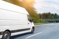 White modern delivery small shipment cargo courier van moving fast on motorway road to city urban suburb. Busines distribution and Royalty Free Stock Photo