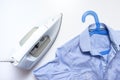 White modern electrical iron close up and blue shirts on the table, top view - ironing, laundry and housework concept