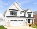 A white modern farmhouse with a black roof.