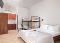 White modern interior of family suit bedroom with classic double bed, bunk bed with metal stairs, wooden kitchen cabinets, in Royalty Free Stock Photo