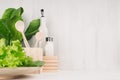 White modern kitchen decor with beige natural wooden dish, utensils, fresh green salad on wood background.