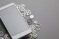 White modern mobile phone with blank gray screen and small gears on table Royalty Free Stock Photo