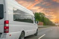 White modern passenger charter van with a small delivery moves fast on the highway to the urban suburbs. Business distribution and Royalty Free Stock Photo