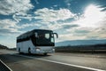 White Modern tourist bus driving through highway on bright sunny sunset Royalty Free Stock Photo