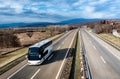 White Modern tourist bus driving through highway on bright sunny sunset Royalty Free Stock Photo
