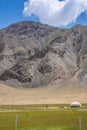 White yurt and a woman on pastures at the foot of mountains