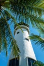 The white monolite structure of the lighthouse rises overover a palms tree. Thailand, Bangok. The massive tower of an