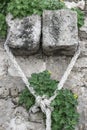 White Mooring Rope knotted on stone wall with green plants. Royalty Free Stock Photo