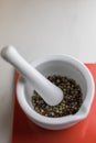 white mortar with colorful pepper inside on a red tile on a marble table