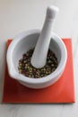 white mortar with colorful pepper inside on a red tile on a marble table