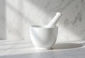 White mortar and pestle on a marble surface, bathed in soft natural light, casting gentle shadows Royalty Free Stock Photo