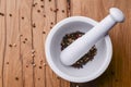 White mortar and pestle with pepper and spices mix on rustic wooden table. Royalty Free Stock Photo