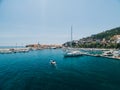 White motor boat sails past the pier of the city of Budva Montenegro on the background of ancient buildings