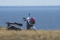 White motor scooter stands on the seashore. Traveling to the sea. Steppe grass, turquoise sea and blue sky