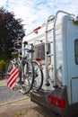 A white motorhome with a cycle carrier attached to the rear, with two bicycles