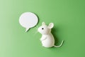 White mouse figurine looking at a blank speech bubble on a green background Royalty Free Stock Photo