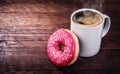 White mug of coffee and a donut on a wooden background