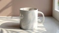A white mug with a handle sits on a marble countertop, with sunlight streaming in from a window Royalty Free Stock Photo