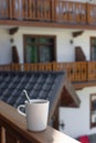 White mug with a hot drink on the balcony of a vintage wooden terrace.