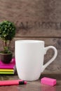 White mug mockup. Blank mug. Coffee mug mockup with bright neon colors pencils and notebooks. Potted plant bonsai behind Royalty Free Stock Photo