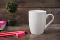 White mug mockup. Blank mug. Coffee mug mockup with bright neon colors pencils and notebooks. Potted plant bonsai behind Royalty Free Stock Photo