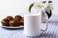 White mug mockup with chocolate muffins on plate and white flowers Royalty Free Stock Photo