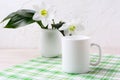 White mug mockup with lily in vase on green checkered napkin