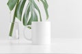 White mug mockup with a monstera leaf in a glass vase on a white table