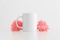 White mug mockup with pink chrysanthemums on a white table