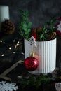 White mug in New Year`s composition, red ball, cinnamon, twigs, clothespin Christmas tree
