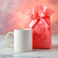 A white mug and a pink gift bag with hearts on a marble surface against a pink and orange backdrop Royalty Free Stock Photo