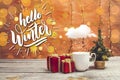 White mug with snowing cloud, present boxes and little Christmas tree with bokeh lights on a wooden table Royalty Free Stock Photo