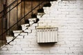 White multi devision mailbox hanging on white brick wall under stairway Royalty Free Stock Photo