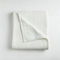 White muslin blanket, neatly folded against a plain background. The fabric features a Royalty Free Stock Photo