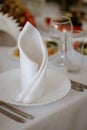 A white napkin folded into a triangle sits on a plate with a fork and knife Royalty Free Stock Photo