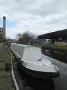 A white narrow boat moored on the canal in an industrial area of huddersfield with mill and bridge Royalty Free Stock Photo