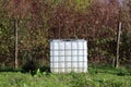 White new intermediate bulk container or IBC plastic tank with metal cage used for water storage left in family house backyard Royalty Free Stock Photo