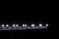 White night bridge with lights with light. Rays of white light from the lanterns, black night. The bridge hovers
