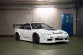 white Nissan Silvia S13 with spoiler and body kit in an underground garage