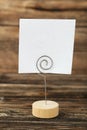 White note paper on a holder on brown wooden background. Royalty Free Stock Photo