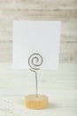 White note paper on a holder on white wooden background. Royalty Free Stock Photo