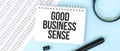 White noteapad and magnifier on the financial documentation. Text GOOD BUSINESS SENSE. Business concept Royalty Free Stock Photo