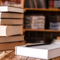 A white notebook and a black pencil on the desktop with bookshelves in the background. Books Royalty Free Stock Photo