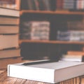 A white notebook and a black pencil on the desktop with bookshelves in the background. Books Royalty Free Stock Photo