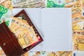 A white notebook with blank pages lay on a set of banknotes of 100 euros, 50 euros and 100 dollars. Royalty Free Stock Photo