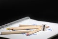 White notebook , color pencils and pencil sharpener on a table against black background. Preparing for a school. Royalty Free Stock Photo